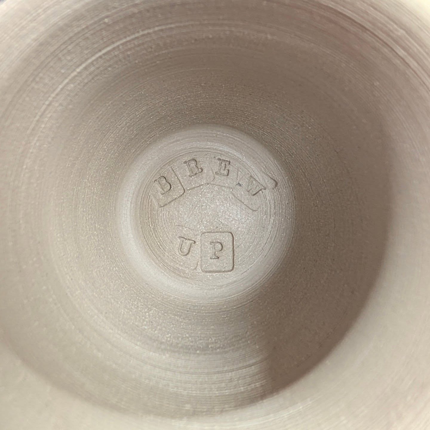 Inside a handmade stoneware mug with a stamped detail