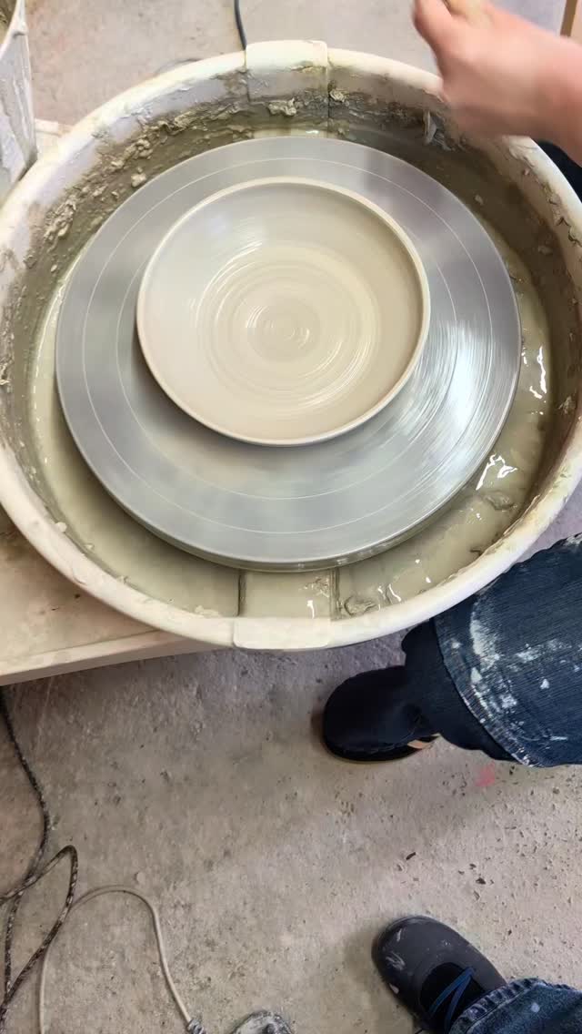 A freshly thrown ceramic plate on the pottery wheel